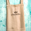 Beige apron with text and Clarence Court logo on a textured blue background